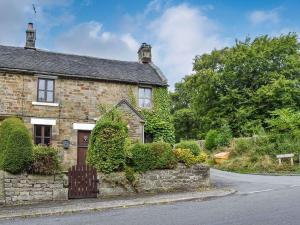 an old stone house with a gate on the street at Gem Cottage in Longnor