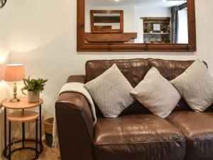 a brown leather couch with pillows in a living room at Gem Cottage in Longnor