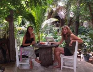 two women sitting at a table in a garden at Sala Thongyon - Guest House in Savannakhet