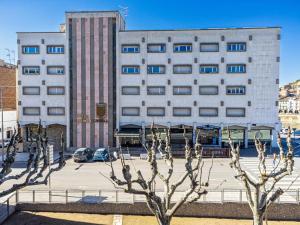 um grande edifício branco com árvores em frente em HOTEL JAUME D'URGELL em Balaguer