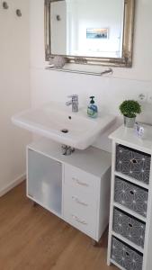 W łazience znajduje się biała umywalka i lustro. w obiekcie Ferienwohnung Beste - für eine entspannte Auszeit w mieście Bad Oldesloe