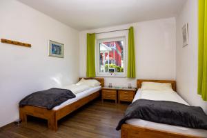 two beds in a room with green curtains and a window at Appartmenthaus Köflach in Köflach