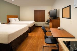 デイビーにあるExtended Stay America Select Suites - Fort Lauderdale - Airport - Westのベッド2台、デスク、テレビが備わるホテルルームです。