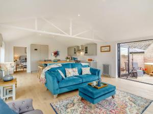 a living room with a blue couch and a kitchen at The Old Workshop in Gipping