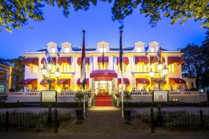 un gran edificio blanco con banderas. en Bilderberg Grand Hotel Wientjes, en Zwolle