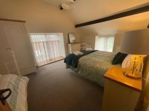 a bedroom with a bed and a table with a lamp at Y Stabl 94a in Denbigh +8 photos