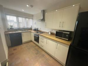 a kitchen with white cabinets and a black microwave at Y Stabl 94a in Denbigh