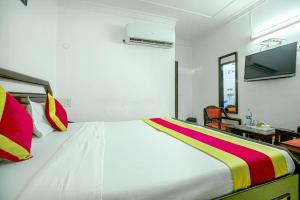 a bedroom with a large white bed with colorful pillows at HOTEL ARINA in Chandīgarh