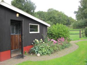 een zwart gebouw met een deur en wat bloemen bij B&B Het Bakhuis in Loenen