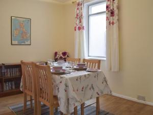a dining room with a table with chairs and a window at Plum Tree Cottage in Harwich