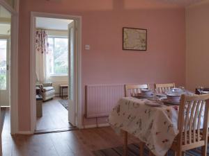 a dining room with a table and chairs and a room with a window at Plum Tree Cottage in Harwich