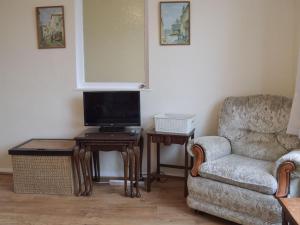 a living room with a chair and a television at Plum Tree Cottage in Harwich