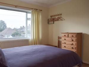 a bedroom with a bed and a window and a dresser at Plum Tree Cottage in Harwich