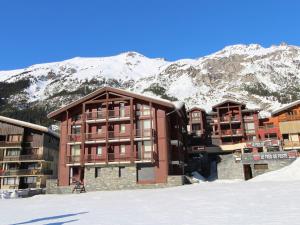 a building in the snow with mountains in the background at Appartement cosy 4 pers - Résidence Le Pied de Pistes, au pied des remontées mécaniques - FR-1-508-23 in Lanslevillard