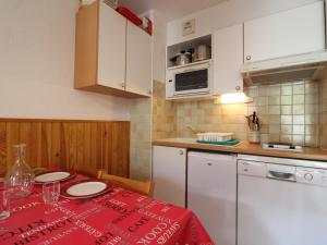a kitchen with a table with a red table cloth at Charmant appart pour 4 au centre de Lanslevillard, balcon, parking - FR-1-508-201 in Lanslevillard