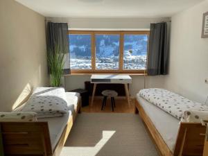 1 dormitorio con 2 camas, escritorio y ventana en Ferienappartement Wachter, en Bartholomäberg