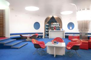 a room with blue carpet and red chairs and tables at Albergo Residence Italia Vintage Hotel in Pordenone