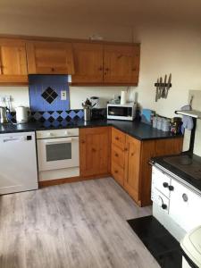 a kitchen with white appliances and wooden cabinets at Conveniently situated three bedroom townhouse in Moville