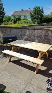 una mesa de picnic de madera y una silla en el patio en Conveniently situated three bedroom townhouse en Moville