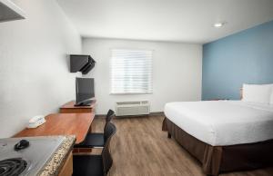 a hotel room with a bed and a desk with a stove at Extended Stay America Select Suites - Gulfport in Gulfport