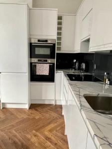 uma cozinha com armários brancos e um forno com placa de fogão em Portobello Living em Londres