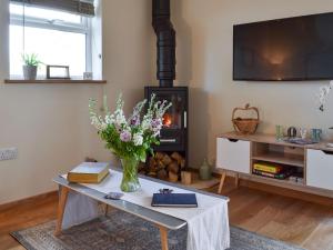 a living room with a table with a vase of flowers at The Hayloft-ukc2489 in Mountfield