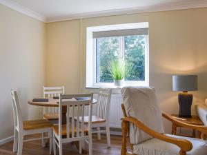 d'une salle à manger avec une table, des chaises et une fenêtre. dans l'établissement Swallow Cottage, à Gowerton