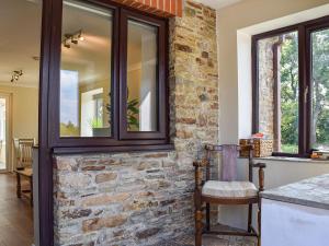 cocina con pared de piedra y ventanas en Swallow Cottage, en Gowerton