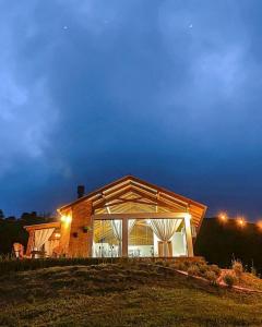 a house with a large window on top of a field at Chalé Caminho do Sol in Rancho Queimado