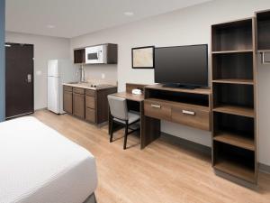 Habitación de hotel con cama y escritorio con TV. en Extended Stay America Suites - Nashua - Merrimack en Merrimack