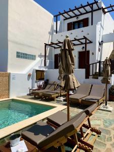 a pool with chairs and umbrellas next to a house at Christina Hotel, Adults Only in Naousa