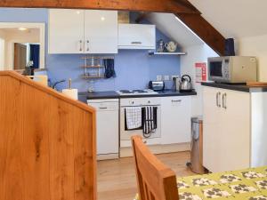 una cocina con armarios blancos y una mesa en una habitación en The Granary, en Westerdale