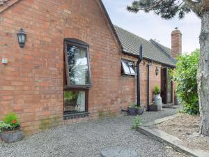 una casa di mattoni rossi con un albero di fronte di The Cotes a Malvern Wells