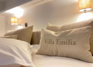 a white bed with a pillow with the word villa emilia at Villa Emilia in De Haan