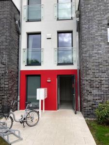 uma bicicleta estacionada em frente a um edifício com uma porta vermelha em Ferienwohnung Troge em Greifswald