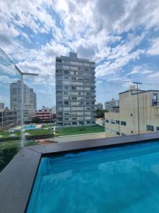a swimming pool in front of a tall building at Edificio Paquebot, en Peninsula, con vista al mar in Punta del Este