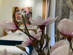 a painting of a man with pink flowers in front of a bed at Apartment z kominkiem w sercu Wrocławia in Wrocław