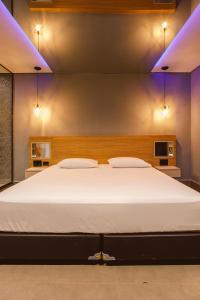 Drops Express Motel في باريتوس: غرفة نوم مع سرير أبيض كبير مع أضواء زرقاء