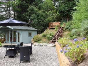 a patio with an umbrella and a table and chairs at Dream Cottage in Strathyre
