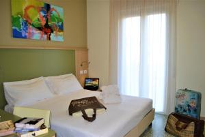 een slaapkamer met een bed met een boek erop bij Hotel La Baia in Diano Marina