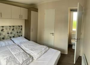 - une chambre avec un lit blanc et des toilettes dans l'établissement Chalet Seeglück O3, à Lathum