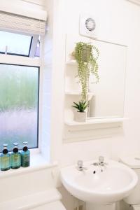 a white bathroom with a sink and a window at Bee Stays - Caldecott House in Manchester