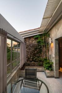 un patio con una mesa de cristal y una pared de piedra. en Motel Aquarius (Adults Only) en Caxias do Sul