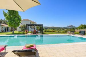 a swimming pool with chairs and an umbrella at Villa Amarandes With Private Pool in Paradeísion