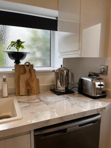 a kitchen counter with a toaster and a tea kettle at The Snug- With Private parking in Whitstable