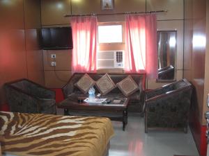 a room with a bed and a table and a couch at Hotel Shiv Ganga in Rishīkesh
