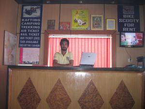 a man standing behind a counter with a laptop at Hotel Shiv Ganga in Rishīkesh