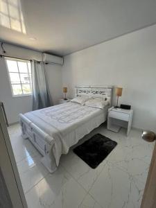 a white bedroom with a large bed and a window at ARNAS HOME in San Andrés