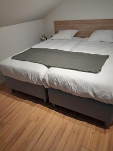 un grande letto in una camera da letto con pavimento in legno di De Hoog Velden 13 a Neerpelt