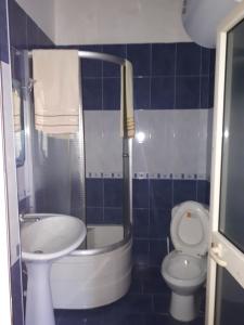a blue tiled bathroom with a toilet and a sink at Hotel Meteor in Shkodër